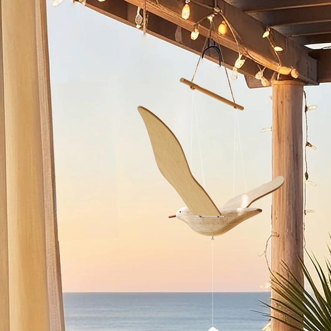 Wooden balancing seagull mobile hanging in a warm coastal interior at sunset.