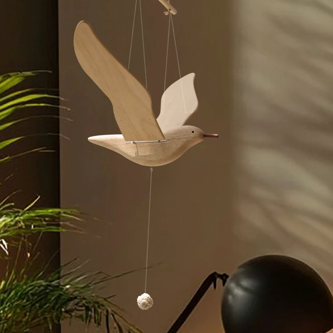 Wooden seagull mobile displayed against a softly lit modern interior with plants.