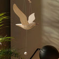Wooden seagull mobile displayed against a softly lit modern interior with plants.