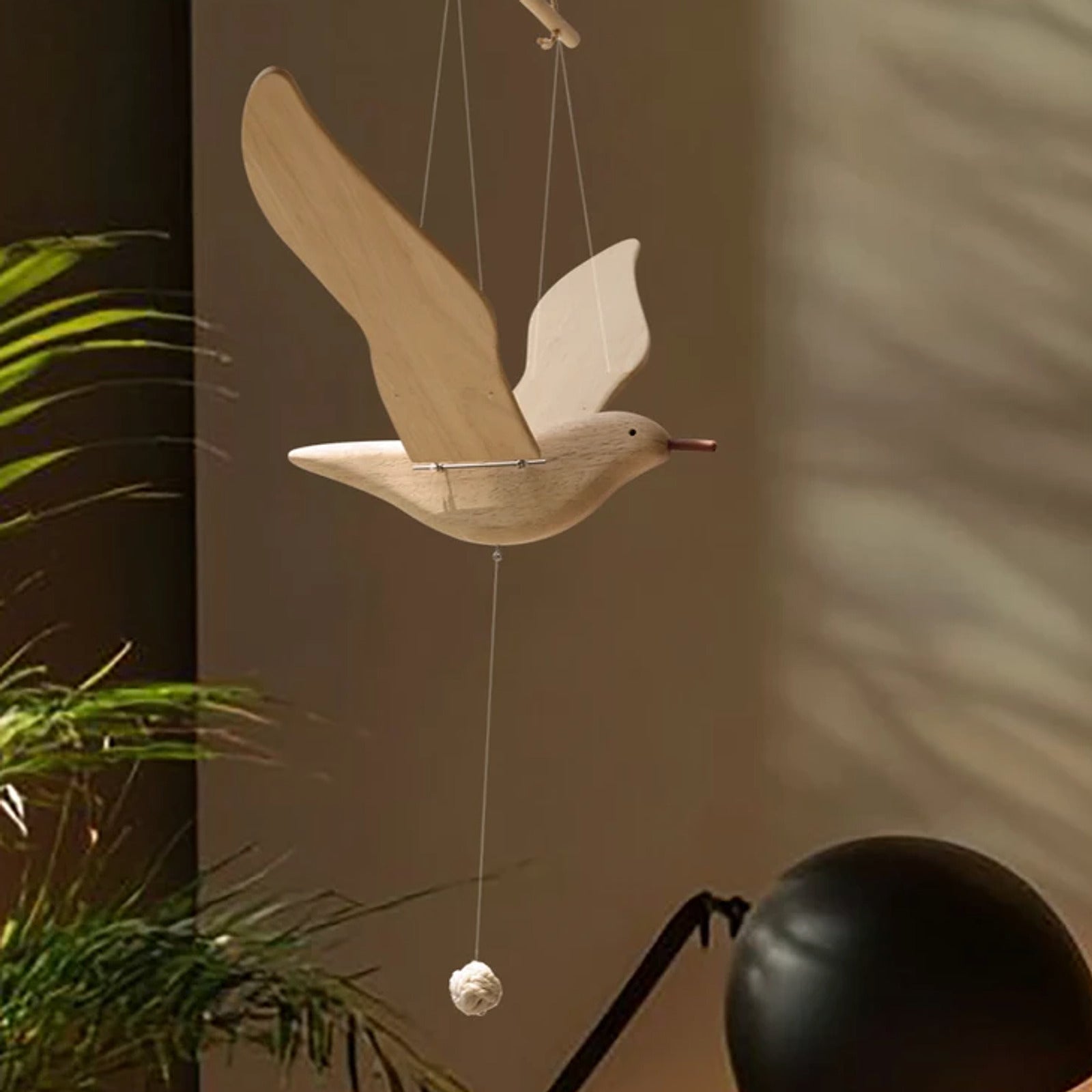 Wooden seagull mobile displayed against a softly lit modern interior with plants.
