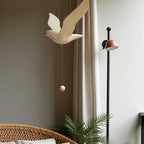 Wooden seagull mobile suspended in a calm bedroom beside a floor lamp.